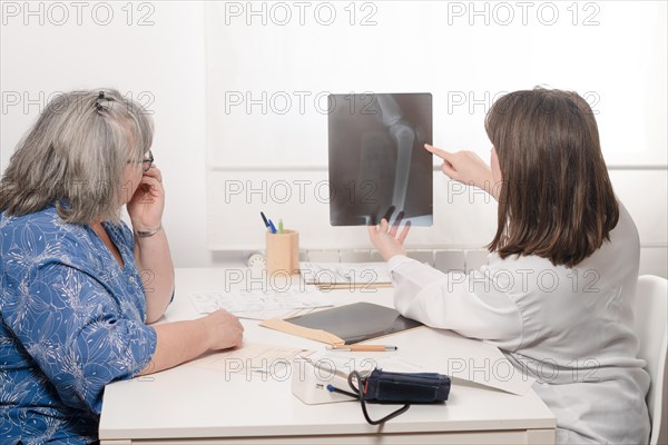 Young woman doctor showing her elderly patient an x-ray