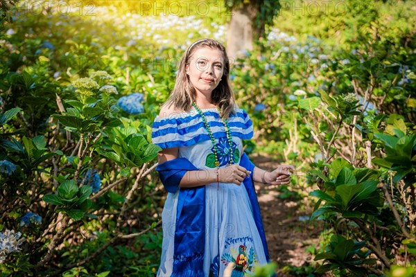 Smiling woman in national folk costume in a field surrounded by flowers. Nicaraguan national folk costume