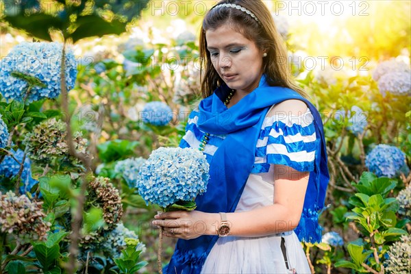 Woman in traditional Central American folk costume holding flowers in a nursery. Beautiful woman in national folk costume holding flowers in a nursery. Nicaraguan folk costume