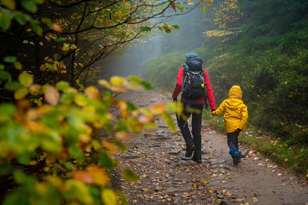 Mum and her little son go on a mountain trail in wet autumn weather. Polish mountains