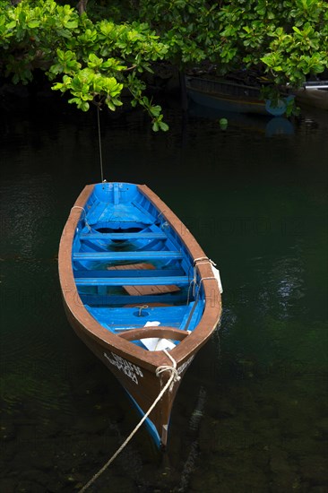 Blue fishing boat lies leashed in