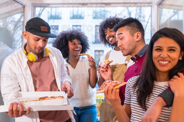 Group of friends eating pizza on the terrace at home