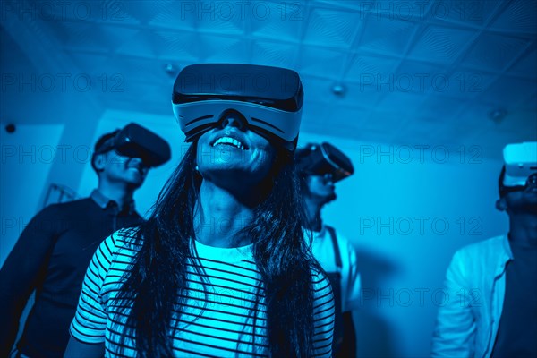 Group of young people with vr glasses in a virtual reality game in a blue light