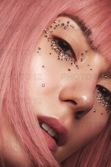 Beautiful woman in a pink wig and creative makeup with rhinestones. Beauty face. Photo taken in the studio