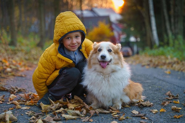 The little kid and his Corgi dog spend time together at sunrise. Fall season