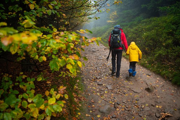 Mum and her little son go on a mountain trail in wet autumn weather. Polish mountains