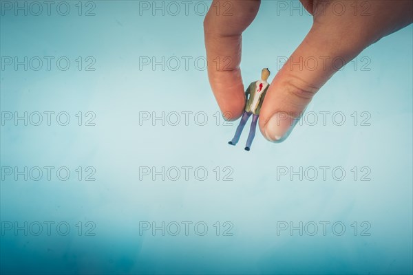 Hand holding a model airplane and a man figurine in blue water