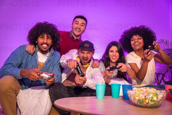 Adult party. Attractive young men sitting on the sofa playing video games with popcorn. Expressing joy while holding the joystick and looking at the monitor