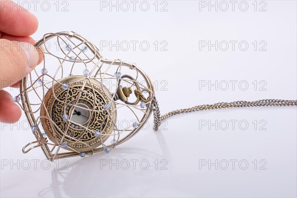 Pocket watch in a heart shaped metal wire cage in hand