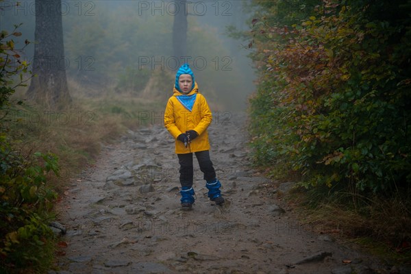 The child is standing on the mountain trail in the raincoat. Polish mountains