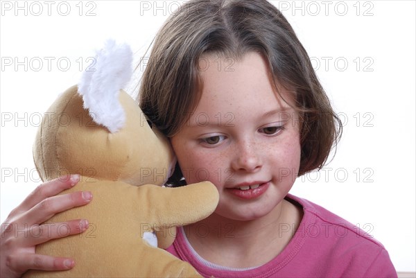Young girl cuddling teddy bear