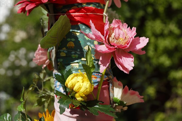 Pole of a streetlamp decorated with colourful artificial flowers