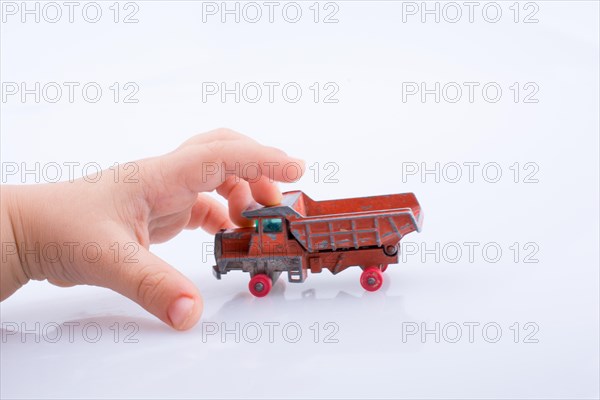 Baby hand is about to grab a red toy truck on white background