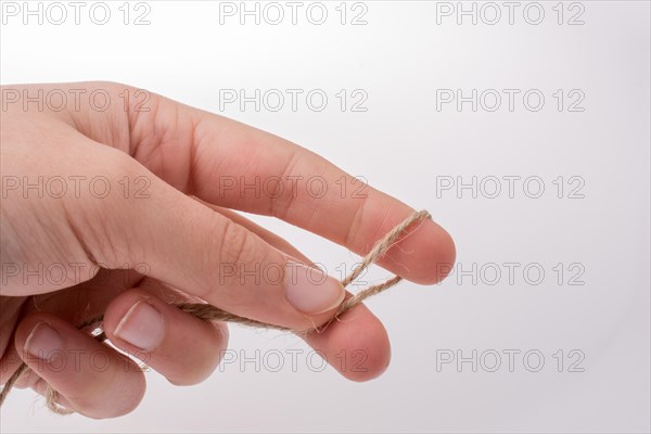 Hand holding linen thread on a white background