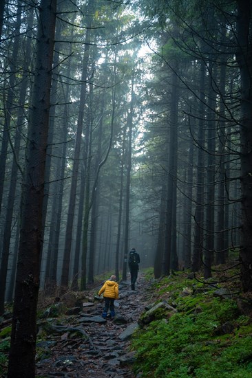 Mum and her little son go on a mountain trail in wet autumn weather. Polish mountains