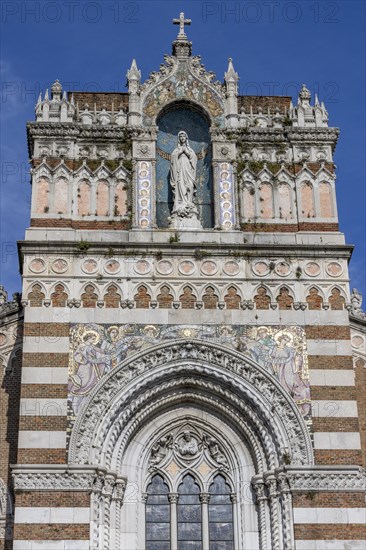 Detail of the top of the facade of the Capuchin Church of Our Lady of Lourdes with a statue of Our Lady of Lourdes decorated with a mosaic