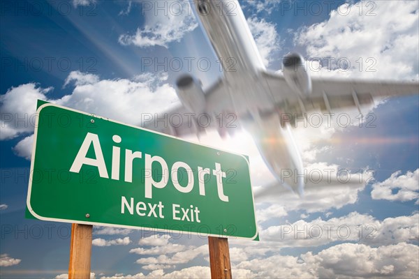 Airport next exit green road sign and landing airplane above