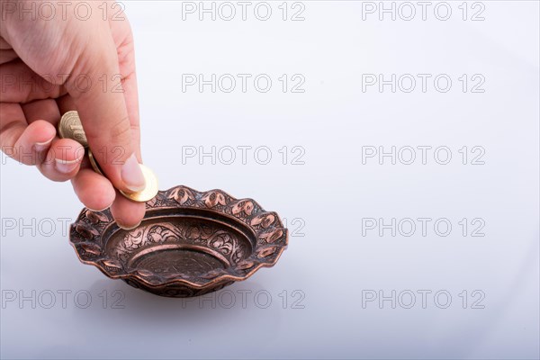 Hand giving away money to a metal bowl