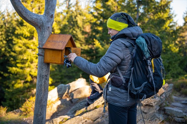 The woman takes a stamp to put a stamp on the beauty of the mountain peak. Polish mountains