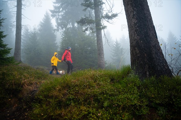 Mum and her little son go on a mountain trail in wet autumn weather. They are accompanied by a dog. Polish mountains