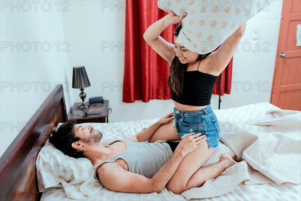 Young couple playing with pillow in bed. Couple in love playing with pillow in bed