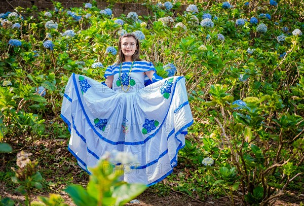 Young Nicaraguan woman in traditional folk costume in a field of Milflores