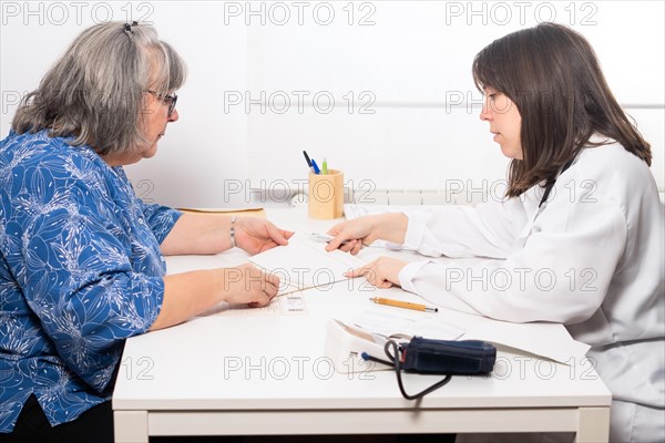 Young female doctor explaining to her elderly patient the results of her blood test at the doctors office