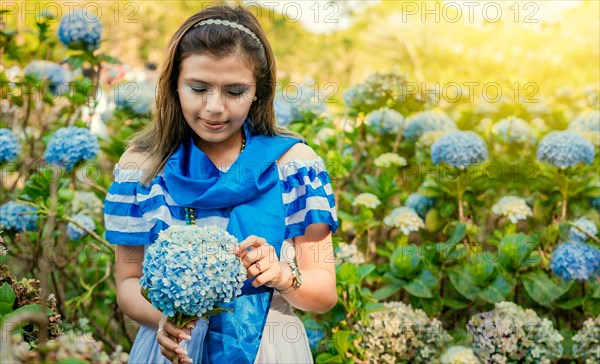 Nicaraguan girl in traditional folk costume holding flowers in a nursery. Beautiful Nicaraguan woman in national folk costume holding flowers in a nursery. Nicaraguan folk costume