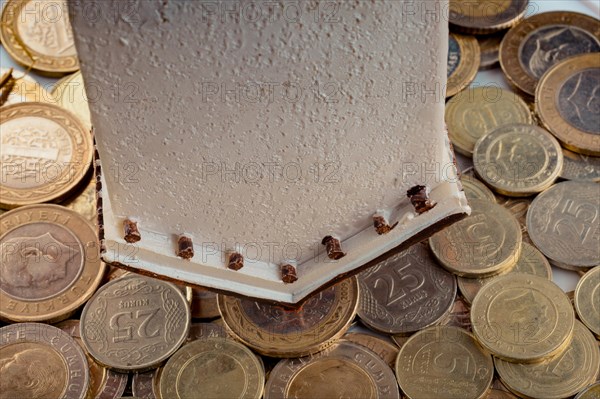 Turkish Lira coins by the side of a model house on white background