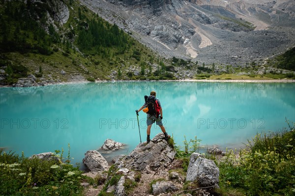 Tourist posing for a photo against the background of the beautiful Lago di Sorapis lake in the Italian Dolomites