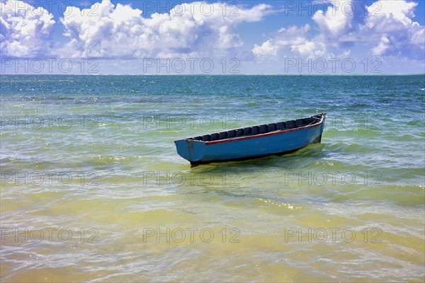 Blue fishing boat bobbing near the beach