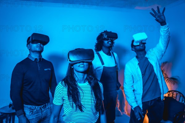 Group of young people with vr glasses in a virtual reality game in a blue light