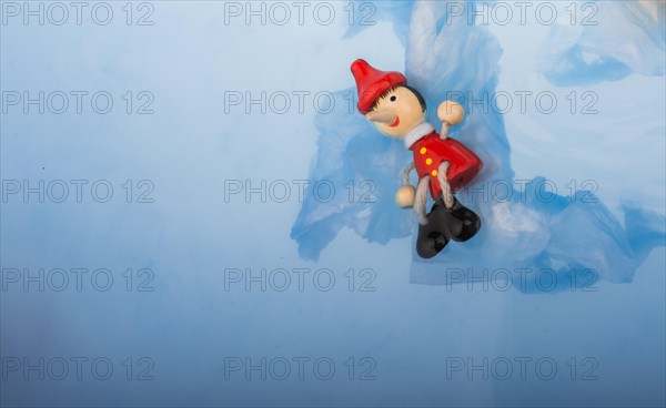 Hand holding wodden puppet Pinocchio on in blue water