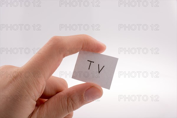 Hand holding a TV written little white paper in with fingers on white background