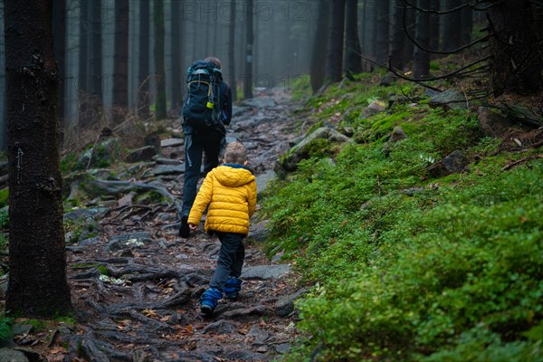 Mum and her little son go on a mountain trail in wet autumn weather. Polish mountains