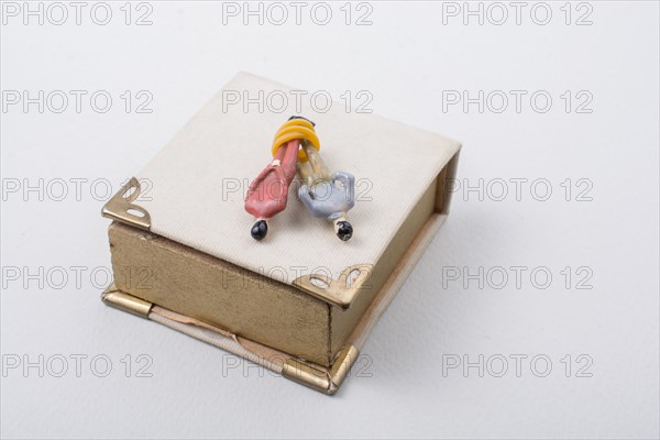 Tiny figurine of men model tied in rope beside a book