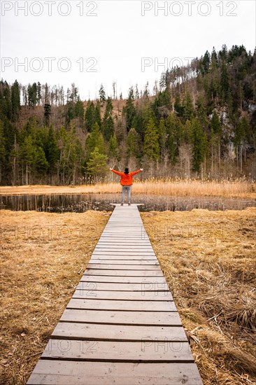 Male hiker on footbridge in front of lake