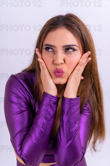 Half body portrait of Latina woman in a studio on a white background dressed in purple leather in profile smiling looking