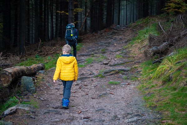 Mum and her little son go on a mountain trail in wet autumn weather. Polish mountains