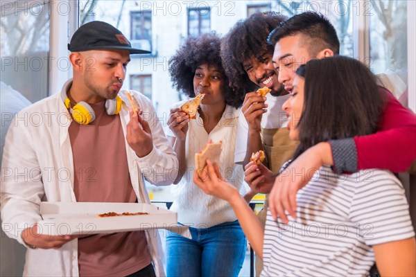 Group of friends eating pizza on the terrace at home