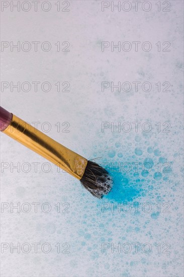 Paint dissolving in water as painting brush touching water