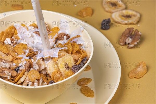 Milk is poured into yellow bowl with cereal