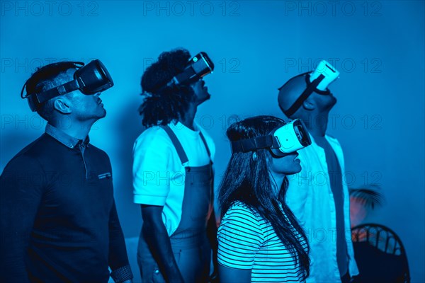 Group of young people with vr glasses in a virtual reality game in a blue light