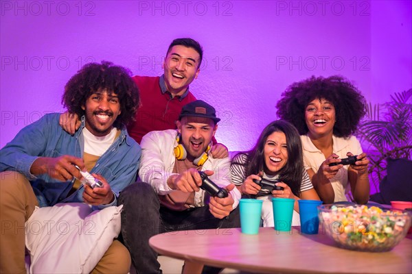 Adult party. Attractive young men sitting on the sofa playing video games with popcorn. With the joystick or controller in hand and look at the monitor