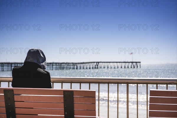 Rear view of a man sitting near Venturas pier and looking at it