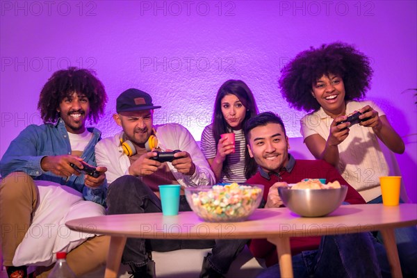 Adult party. Attractive young men sitting on the sofa playing video games. Expressing joy while holding the joystick and looking at the monitor