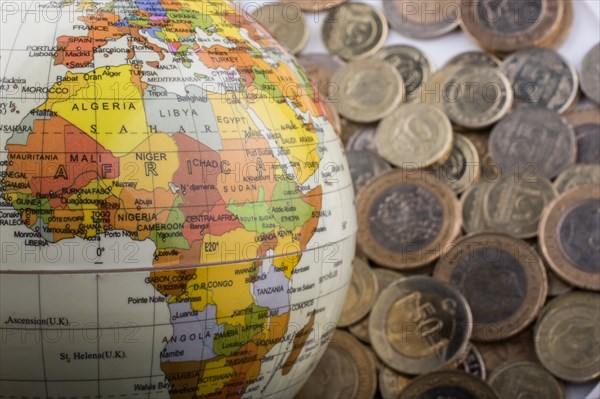 Turkish Lira coins by the side of a model globe on white background