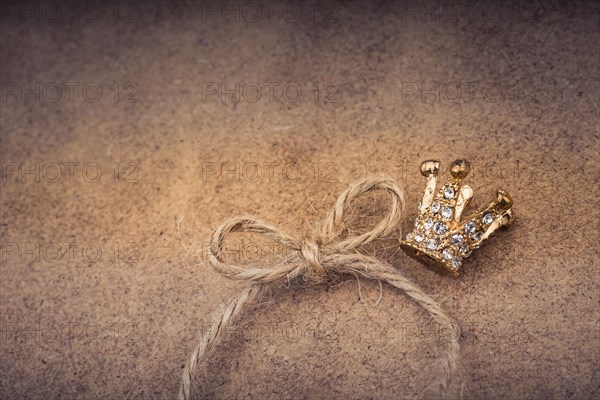 Golden color crown model with pearls on brown background