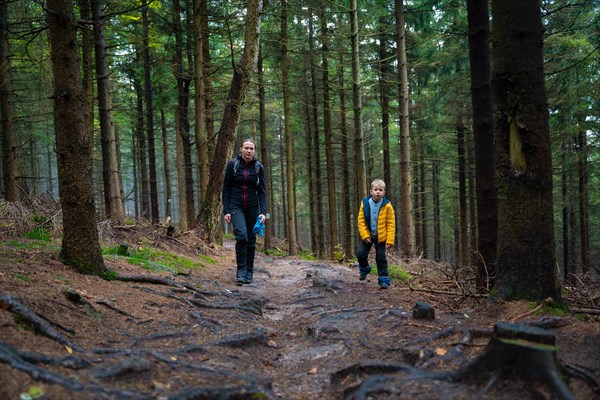 Mum and her little son go on a mountain trail in wet autumn weather. Polish mountains