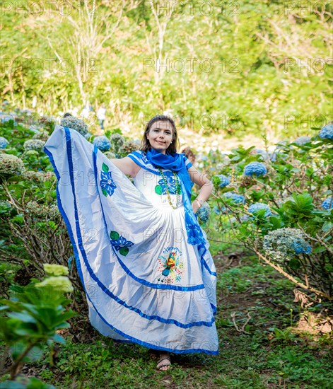 Smiling woman in national folk costume in a field surrounded by flowers. People in Nicaraguan national folk costume. Nicaraguan woman in traditional folk costume in a field of Milflores